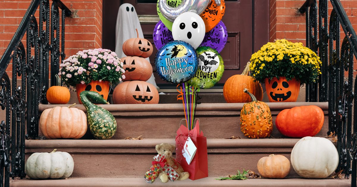 Halloween balloon bouquet, gift bag, and teddy bear on front door step